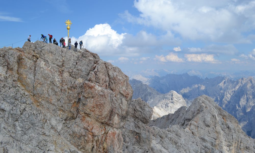 A Group of trekkers standing behind the direction sign board in a mountain peak