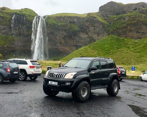 Iconic Jeep Compass Standing On The Sides of The Waterfall In Forest.